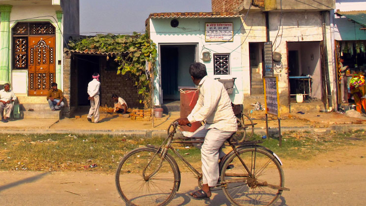 Man ridding bicycle on street in rural India