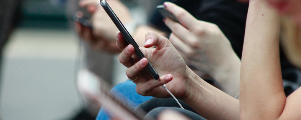 blurred image of a line of hands holding mobile phones