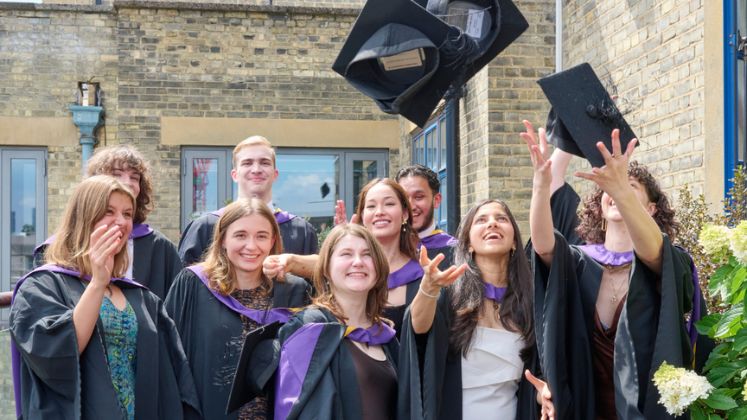 graduates throwing hats in air at july 2024 graduation