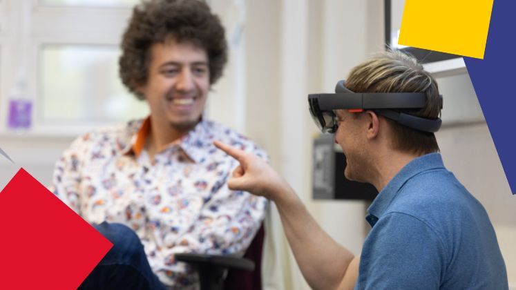 16_9_phd_student_with_vr_headset_taking_to_faculty_member_with_squares