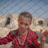Girl_behind_fence_at_refugee_camp_stock_image_from_Canva