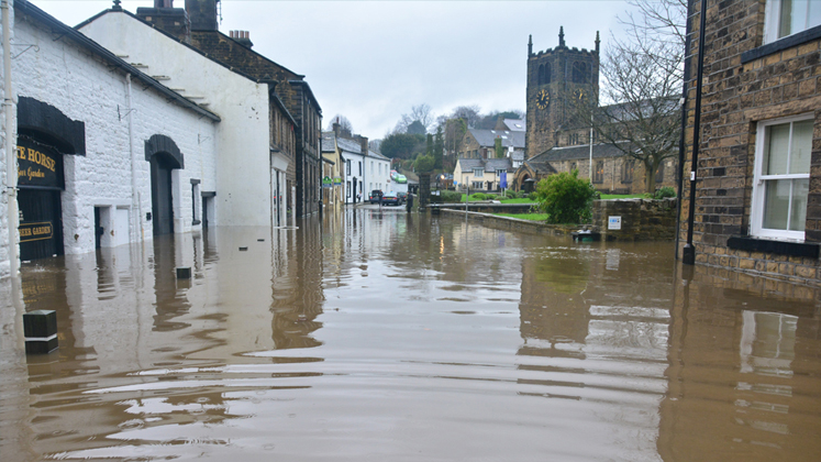 An English street of small houses and a church are flooded