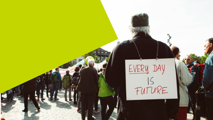 A man walks with a sign on his back which says 'every day is future'