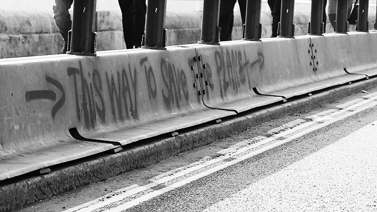 Graffiti on Waterloo Bridge during an environmental protest saying, "this way to save the planet"
