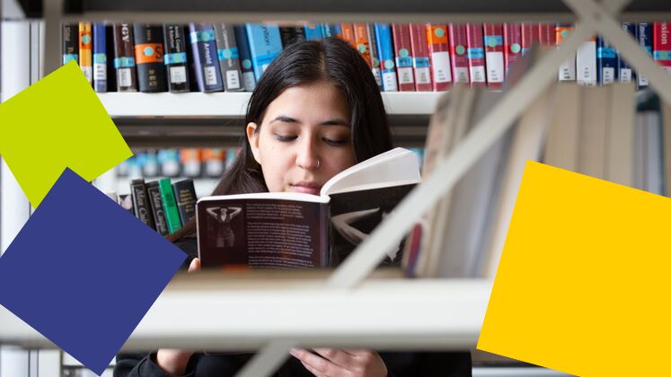 student looking at book in library stacks