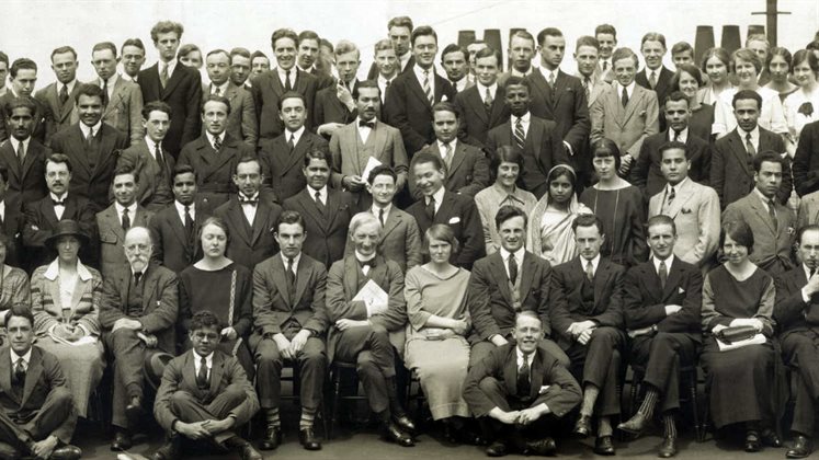 A traditional all school photo where a large group of people are seated and standing looking at the camera for a group photo.
