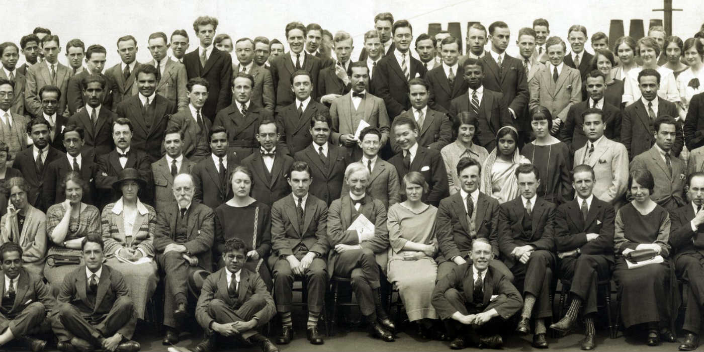A traditional all school photo where a large group of people are seated and standing looking at the camera for a group photo.