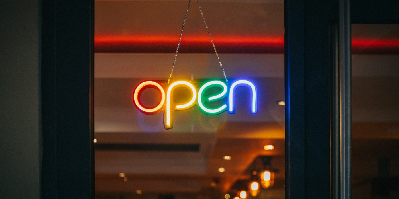 An Open sign hanging in a window. The letters are lit up in rainbow colors