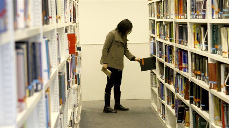 Person in the shelves picking up a book