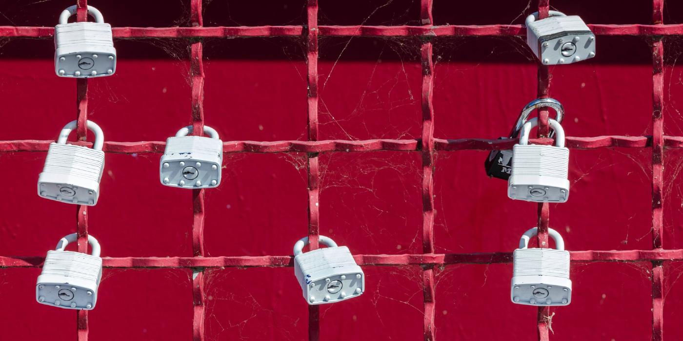 A red metal fence with many white padlocks attached to it