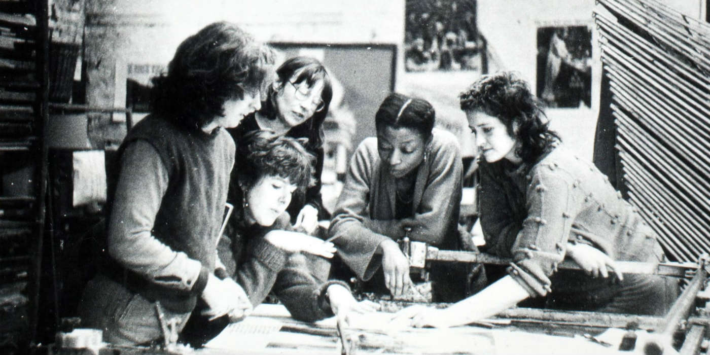 A group of 5 women working on and discussing something related to design.