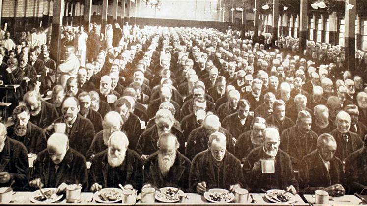 Workhouse dinner with lots of men lined up eating.