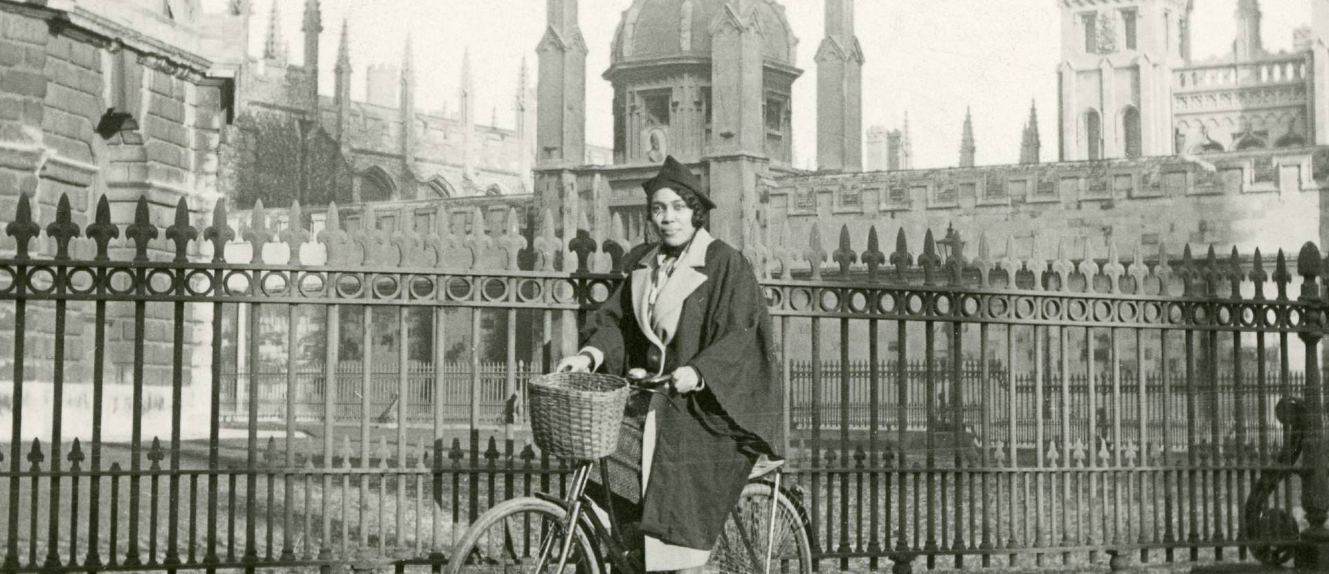 A person in university clothing riding a bike in Oxford