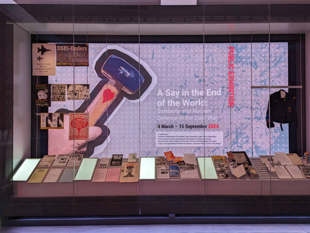 A view of documents in a large viewing case with a video wall in displaying exhibition promotional material.