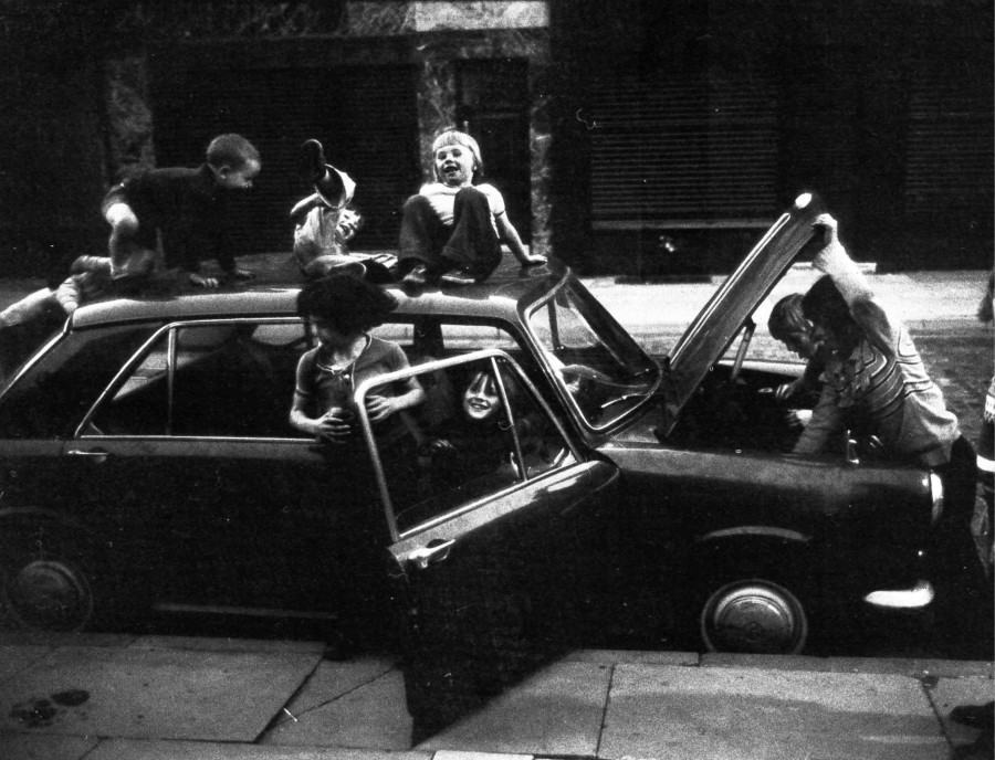 Children playing on and around a car