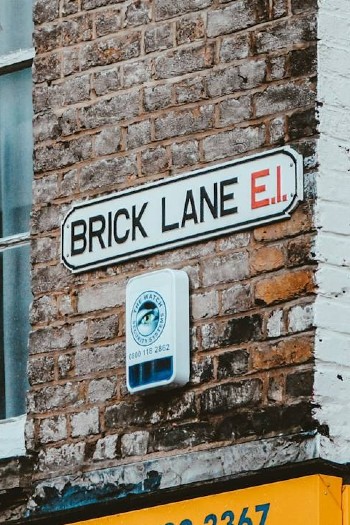 A brick wall with a Brick Lane E1 street sign