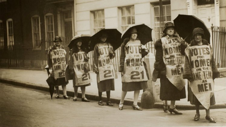 A group of women walking with banners and umbrellas