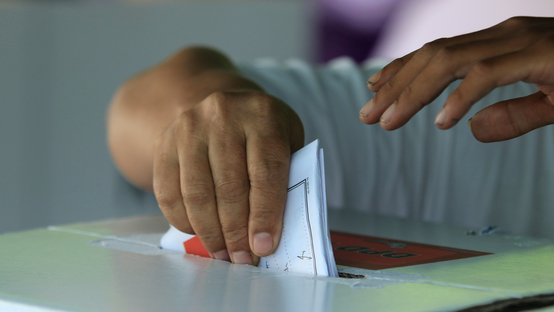 Person posting a ballot into a voting box